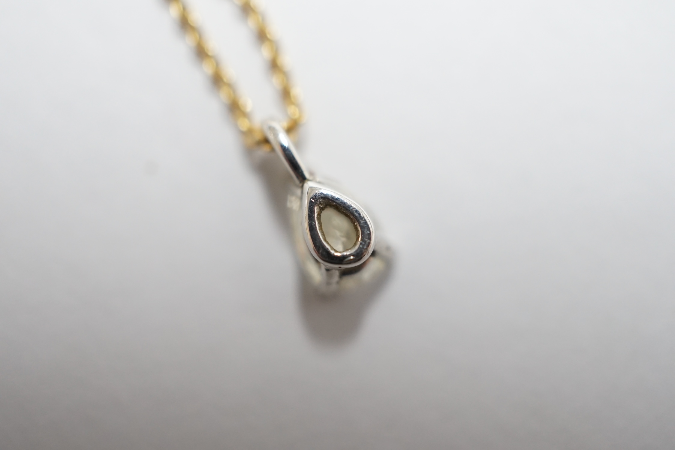 A white metal and pear shaped diamond set pendant, overall 7mm, on a fine link 18ct gold necklet, in a Tiffany & Co box. Condition - good